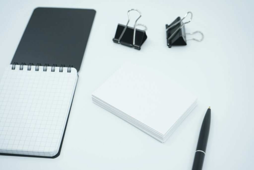 white and black notebook beside black pen